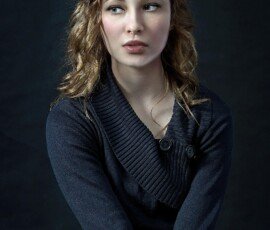 Studio portrait demonstrating MixPlay’s AI outfit and hairstyle preview features. Studio portrait of a woman with short wavy blonde hair wearing a navy sweater.