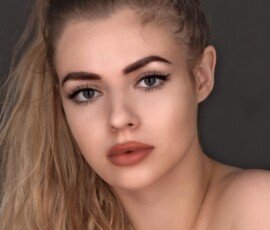 Sample hairstyle portrait showcased for MixPlay AI hair transformations. Young woman with long blonde ponytail and natural makeup against a dark background.